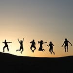 Sechs Silhouetten von Menschen, die während des Sonnenaufgangs springen